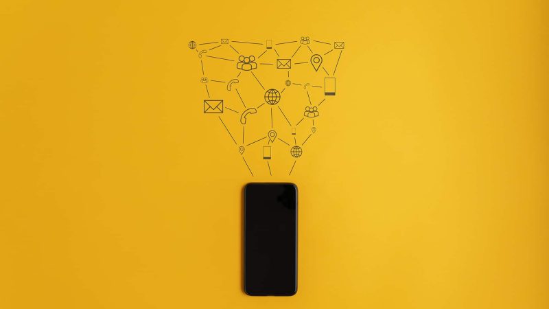 Hand drawn icons of communication and information coming out of a cell phone in conceptual image. Over yellow background.